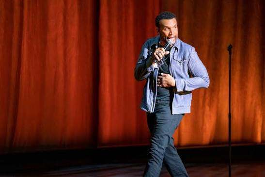 A comedy host on stage in front of a full room